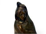 a bronze statue of a woman with a hood on her head