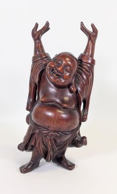 une image représentant une statue d'un Bouddha souriant assis sur une souche d'arbre