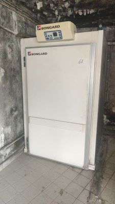 a white refrigerator in the corner of a dirty room