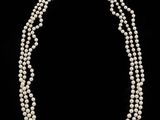 a three strand pearl necklace on a black background