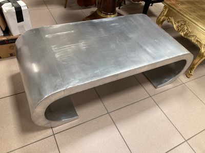 a silver coffee table with a gold base in a room