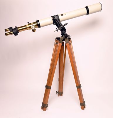 un vieux télescope posé sur un trépied, devant un fond blanc