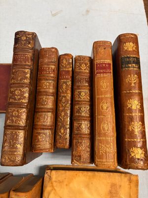 Plusieurs vieux livres sont alignés sur une table à côté d'une bibliothèque.
