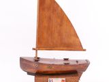 maquette en bois d'un petit voilier posée sur un socle en bois