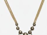 un collier en or orné de perles noires et blanches montées sur une chaîne en or