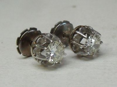 deux paires de boucles d'oreilles en diamant posées sur une surface blanche
