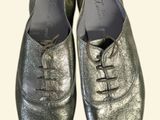pair of silver leather shoes with laces on them on a white background