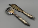 pair of antique silver plated serving utensils on a table