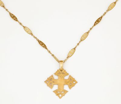 un collier en or avec une croix suspendue à une chaîne