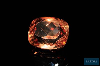 a close up of an orange diamond on a black surface
