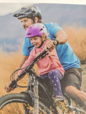 a man riding a bike with a little girl on it