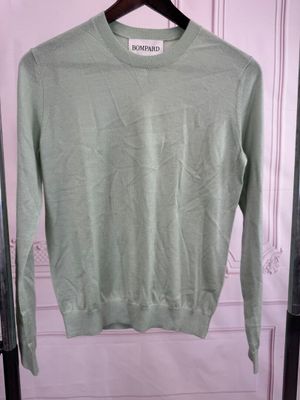 un pull vert suspendu à un cintre devant une porte