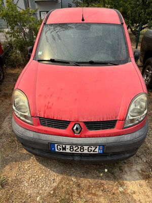 une voiture rouge garée sur la terre battue