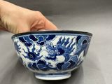 someone holding a blue and white bowl with a dragon design on it