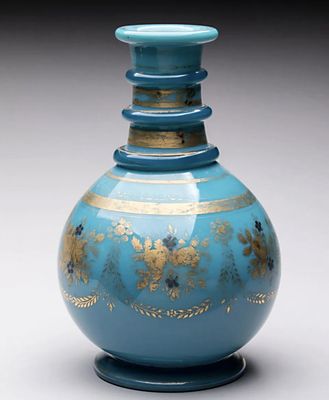 un vase bleu orné de motifs dorés, posé sur un socle