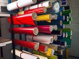 de nombreux rouleaux de vinyle coloré posés sur un support dans une pièce