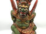 statue d'un démon verte et rouge tenant un couteau