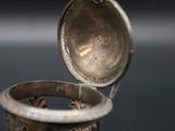 an old silver ring sitting on top of a table next to a cup