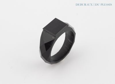 a black ring on a white surface with a black stone in the middle