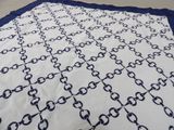 a white and blue blanket on a bed with a black and white blanket