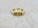 a close up photo of a yellow sapphire and diamond ring on a marble surface