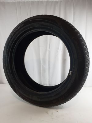a close up of a tire on a white surface with a white curtain in the background