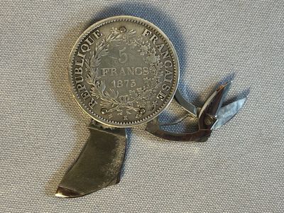 une médaille d'argent entourée d'un ruban, posée sur un morceau de tissu