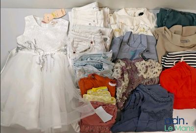 une boîte blanche remplie de vêtements et des vêtements posés sur une table
