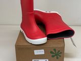 des bottes en caoutchouc rouges posées sur une boîte en carton, sur une surface blanche