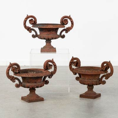 three antique cast iron urns on pedestals in a room