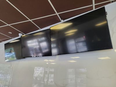 trois téléviseurs fixés au mur dans une grande pièce