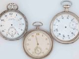 three different types of pocket watches displayed on a white surface