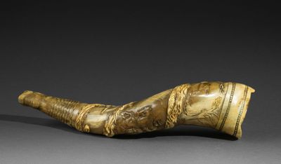 a large horn with a carved handle on a black surface
