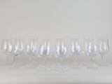 six empty wine glasses lined up in a row against a white background