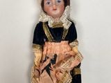 a doll that is wearing a dress and holding a teddy bear