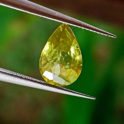 a close up of a yellow diamond being held by a pair of tongs