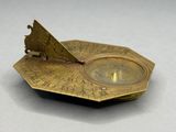 an antique brass sundial with a bird on top of it