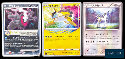 Trois cartes Pokémon sont posées sur une surface noire