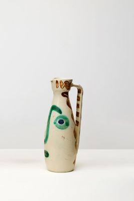 un vase blanc orné d'un visage vert