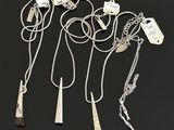 three silver necklaces with tags attached to them on a black surface