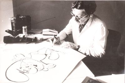 photographie en noir et blanc d'un homme assis à un bureau en train de dessiner