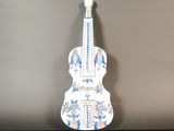 un objet en forme de guitare, blanc et bleu, posé sur une table