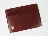 un porte-cartes en cuir marron orné d'un emblème en forme de couronne sur le devant