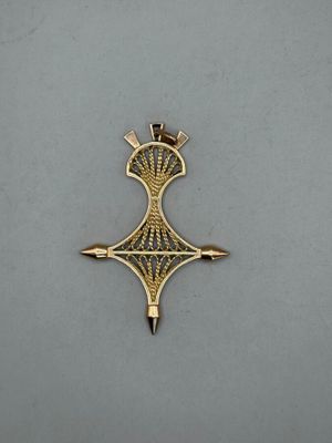 a gold cross with a crown on it sitting on a table