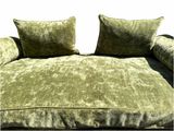 un canapé vert avec deux coussins dessus et un coussin sur le dossier