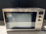 a microwave sitting on a table with a bottle of water in front of it