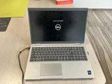 a dell laptop computer sitting on a desk next to a book