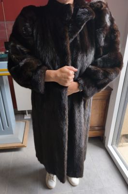 un homme vêtu d'un manteau de fourrure, debout dans une cuisine près d'une fenêtre