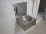 a stainless steel sink in the corner of a public restroom