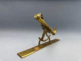 un télescope ancien en laiton posé sur un socle, sur une surface blanche